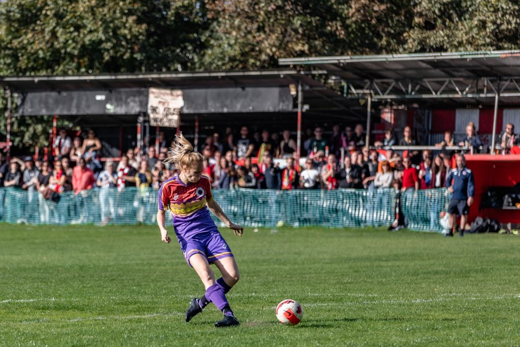 Emily Link shoots on goal with fans in the scaffold looking on