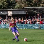 Emily Link shoots on goal with fans in the scaffold looking on